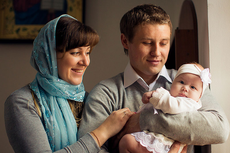 Крестные родители держат младенца